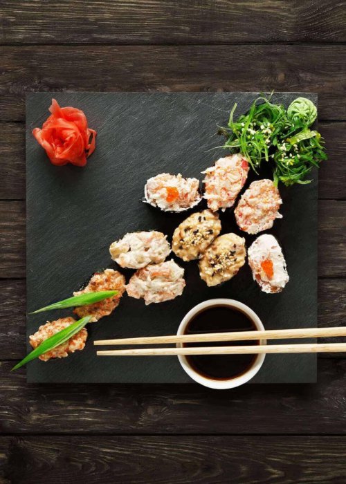 Sushi-Variation mit Ingwer, Algen, Sojasauce und Stäbchen auf Schiefer bei KOSIS Restaurant